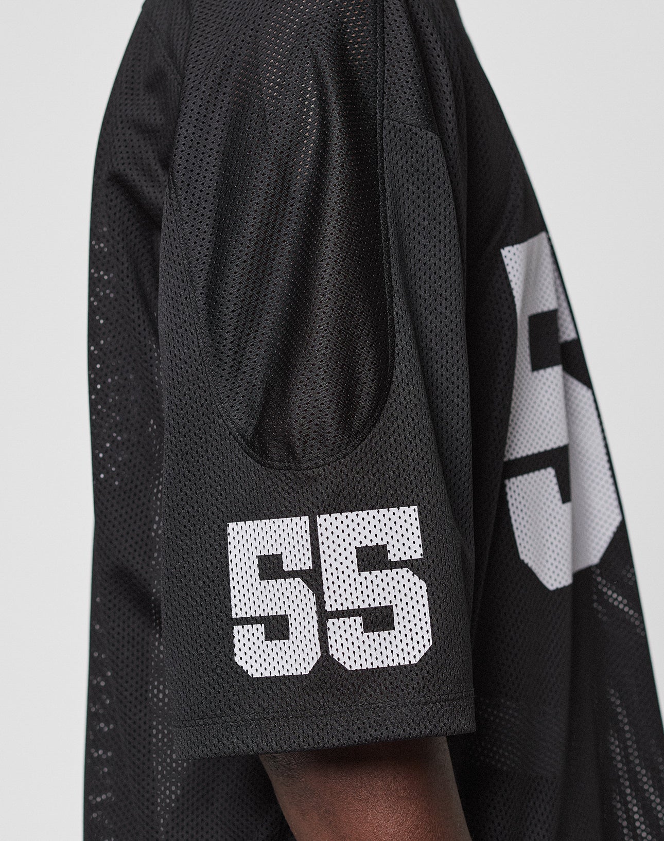 A close-up of a person wearing the black LFDY Mesh Jersey by LIVE FAST DIE YOUNG, featuring a white number 55 on the sleeve and back, V-Ausschnitt, and Oversize Fit.