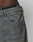 Close-up of a person wearing LFDY Coated Baggy Denim by LIVE FAST DIE YOUNG in faded blue, showing the front pocket and waistband details, paired with black underwear featuring LIVE on the waistband.