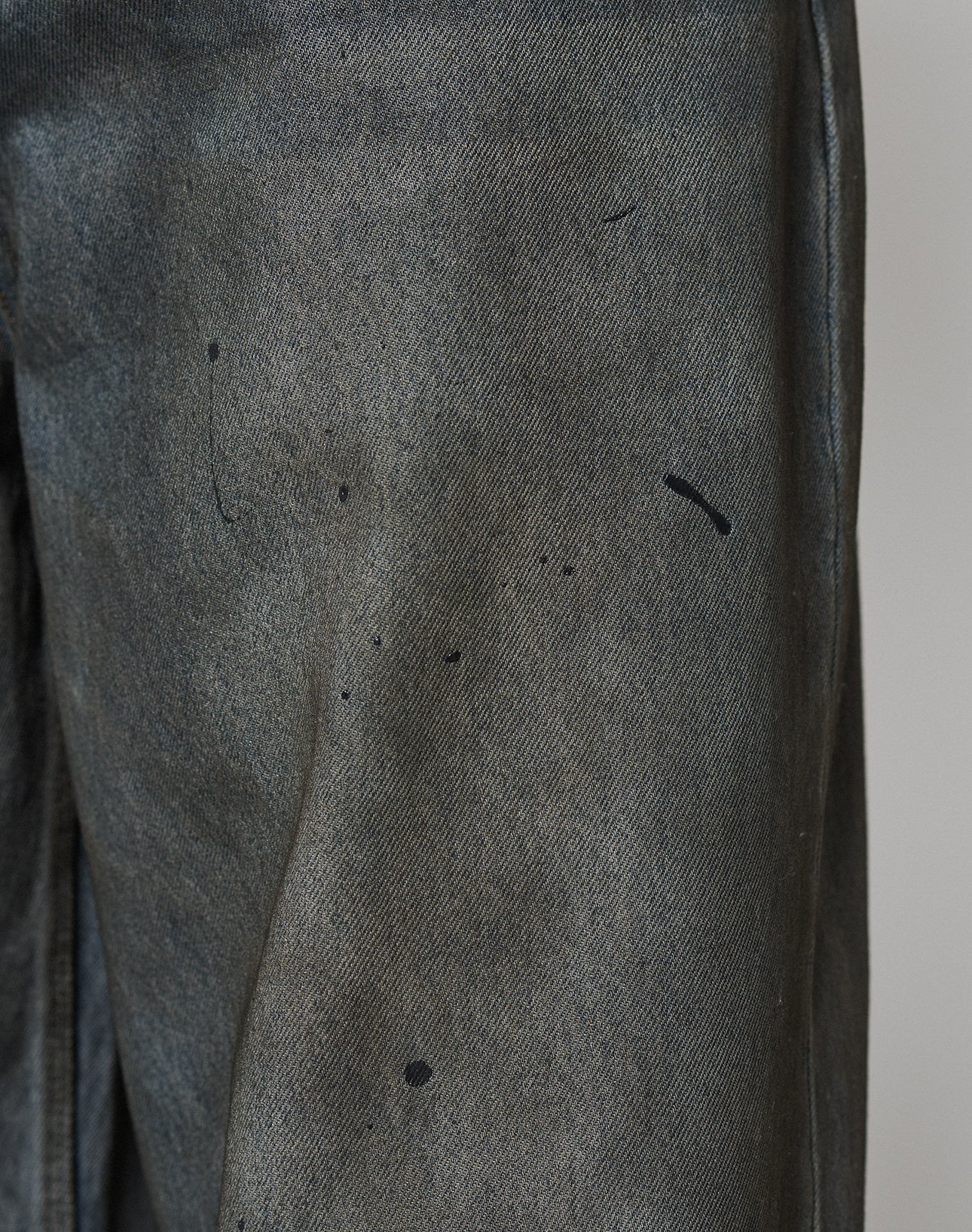 Close-up of LFDY Coated Baggy Denim by LIVE FAST DIE YOUNG, featuring a baggy fit with a wide straight leg and visible black paint splatters on slightly faded Baumwolle fabric.