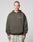 A person with short hair wears the LIVE FAST DIE YOUNG Live Fast Plain Hooded in dark olive, oversized fit with LIVE FAST on the chest, made from a soft cotton-polyester blend, paired with light marble pants against a gray background.