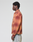 A person stands in profile against a plain background, wearing an oversize fit LIVE FAST DIE YOUNG Vintage Flannel with a red and orange plaid pattern and light blue jeans in vintage wash.