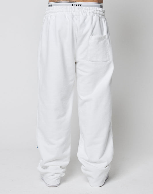 Model wears the LFDY Radiator Sweatpants by LIVE FAST DIE YOUNG—loose-fitting white pants with an elastic waistband, bold black text, and a single back pocket. The oversize fit creates a relaxed, modern look against a plain background.