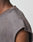 Close-up of a person wearing the LFDY Flames Muscle Shirt by LIVE FAST DIE YOUNG, a grey 100% Baumwolle top with an oversize fit, featuring visible distressing and small holes along the shoulder seam against a plain background.