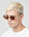 A young man with short, bleached blond hair wears LIVE FAST DIE YOUNG’s Live Fast Sunglasses, featuring translucent brown Mazzuchelli Acetate frames. He sports a white T-shirt and looks slightly downward against a plain light gray background.