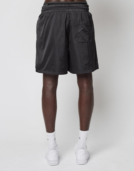 A person stands facing away, wearing LIVE FAST DIE YOUNG LFDY Retro Satin Shorts, white crew socks, and white sneakers against a plain light gray background.