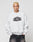 A person with short bleached blond hair wears the LFDY Emblem Sweater by LIVE FAST DIE YOUNG, an Oversize Fit light gray sweatshirt with LIVE FAST in bold black letters, standing against a plain light background.