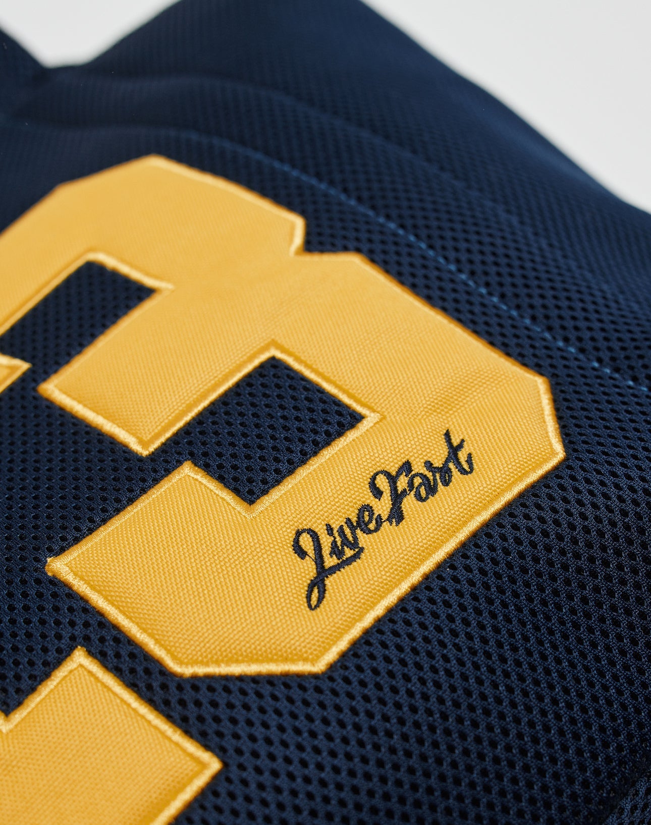 Close-up of the LIVE FAST DIE YOUNG LFDY Mesh Beach Bag in navy blue mesh, featuring large yellow numbers, a convenient mesh pocket, and Live Fast embroidered in black script near the bottom.