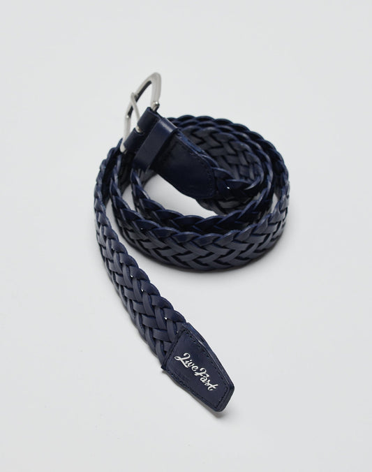 A navy blue LFDY Braided Belt aus 100% Kuh Leder mit silberner Schnalle liegt gerollt auf grauem Untergrund. Auf der Gürtelschlaufe steht LIVE FAST DIE YOUNG in weißer Schrift.