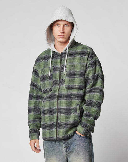 A man wears a LIVE FAST DIE YOUNG Vintage Padded Hooded Flannel, featuring a gray hood with waffle lining and green-black plaid, standing with a neutral expression against a plain light background.