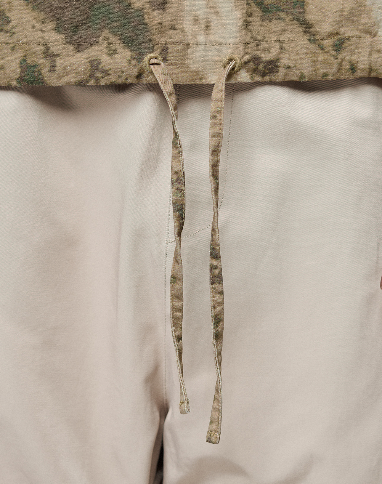 Close-up of the LFDY Camo Halfzip Jacket by LIVE FAST DIE YOUNG, featuring a tan and green camouflage waistband, front drawstrings, and an Oversize Fit for casual comfort. Made from 100% Baumwolle.