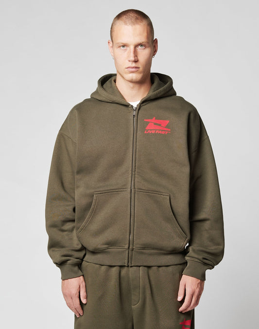 A man with short hair wears the LIVE FAST DIE YOUNG Live Fast Sweatsuit Jacket and matching pants in olive green with red logos, standing forward with a neutral expression against a plain light gray background.
