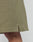 Close-up of the hem of LIVE FAST DIE YOUNG Basic Knit Shorts in olive green ribbed knit, with a small side slit, elastischer Bund, and regular fit. Part of a person’s leg is visible.