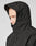 A person wearing the LIVE FAST DIE YOUNG Basic Shell Jacket, black with hood up, shown from the side against a plain background. The oversize fit and water-resistant zipper offer comfort and protection, partially covering the face.