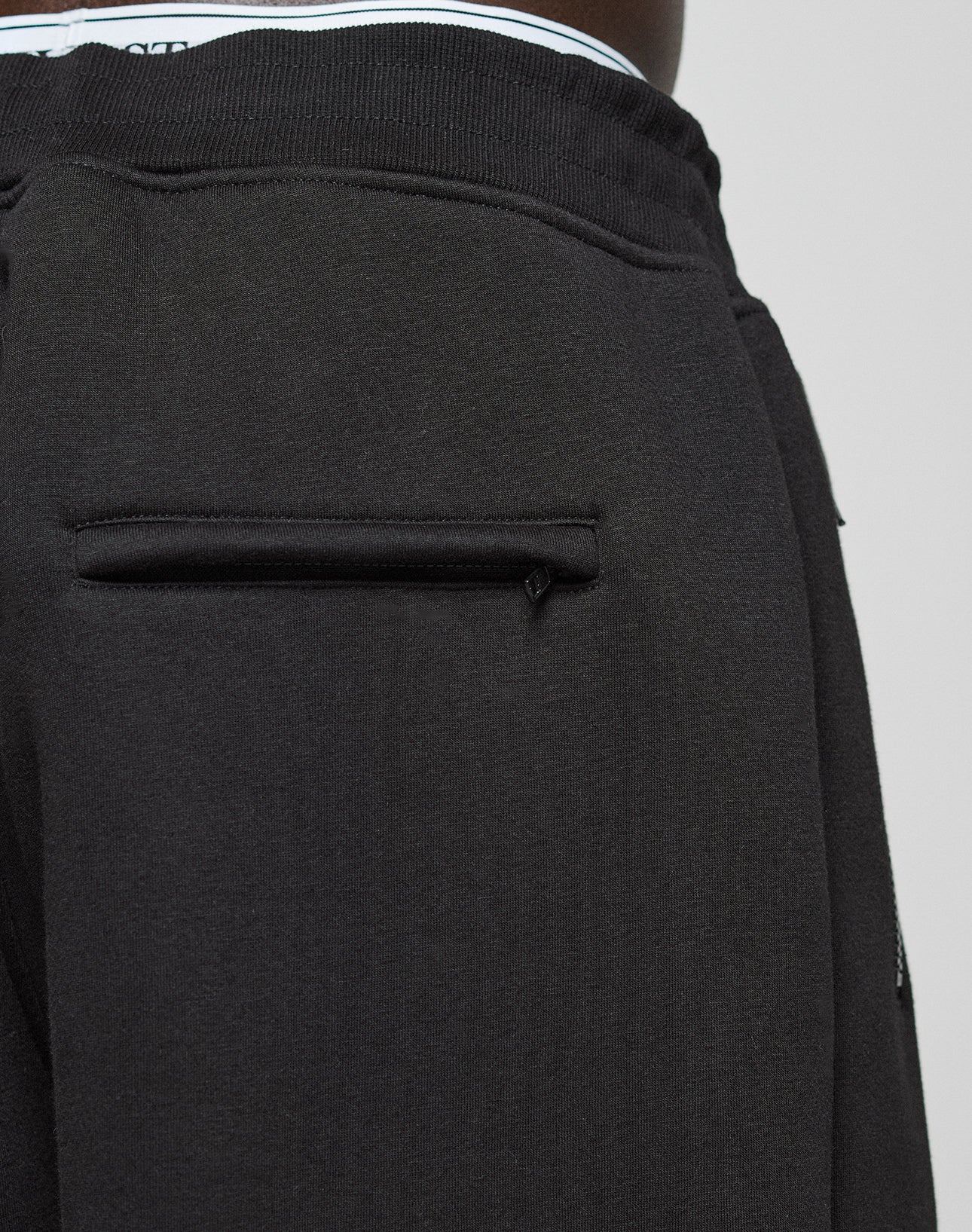Close-up of the LFDY Active Fleece Jogger by LIVE FAST DIE YOUNG, featuring a black back pocket with pull tab, subtle logo print detail, and waistband with a glimpse of striped elastic band.