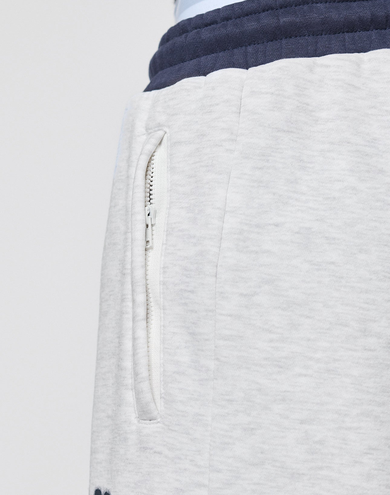 Close-up of the LFDY District Jogger by LIVE FAST DIE YOUNG: light gray sweatpants with side zip pockets and a contrasting dark blue waistband.