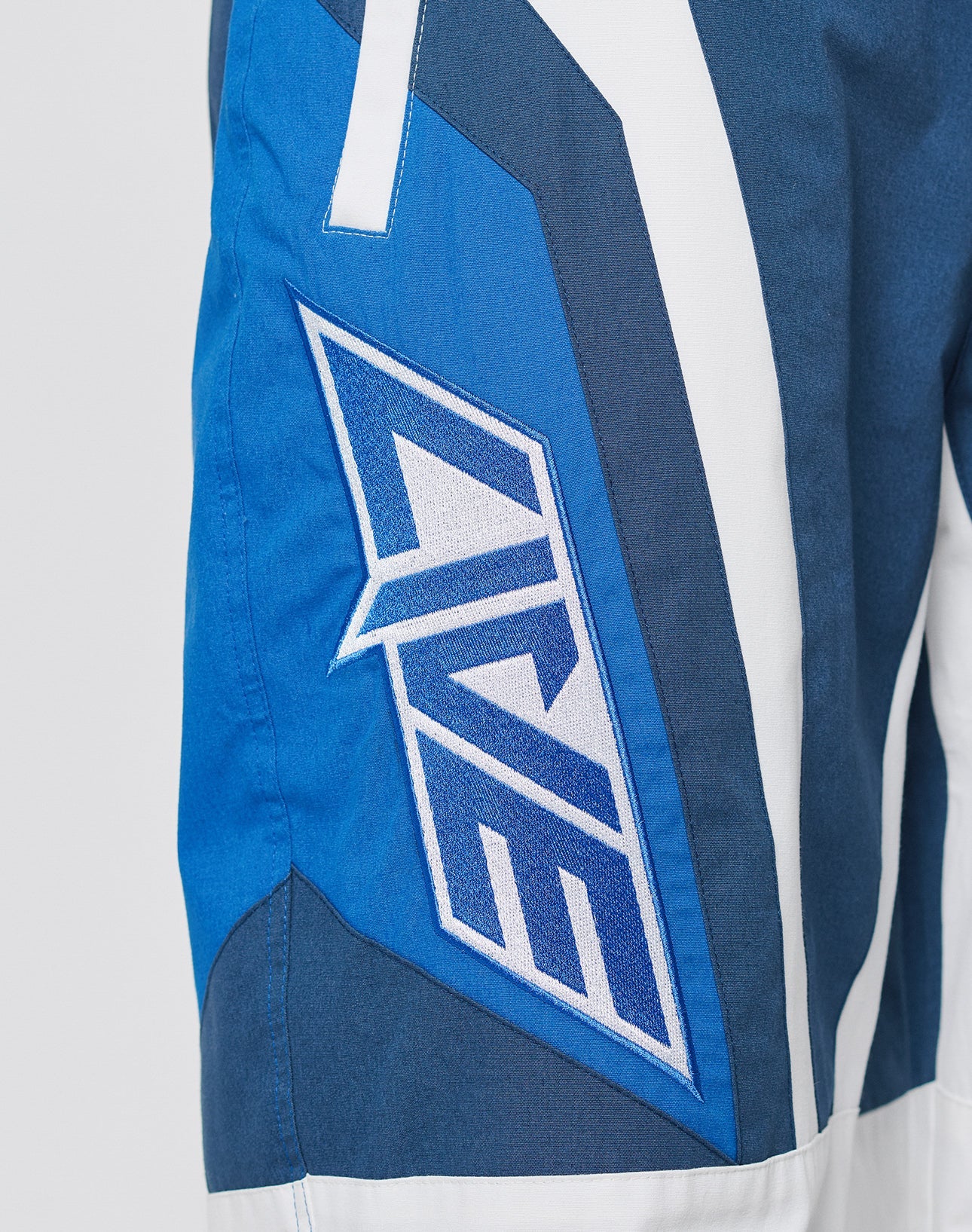 Close-up of LFDY Cross Pants by LIVE FAST DIE YOUNG—blue, white, and navy athletic shorts with an oversize fit, LIVE boldly embroidered in white with blue outline. Features a comfortable Elastikbund and soft Baumwolle fabric.