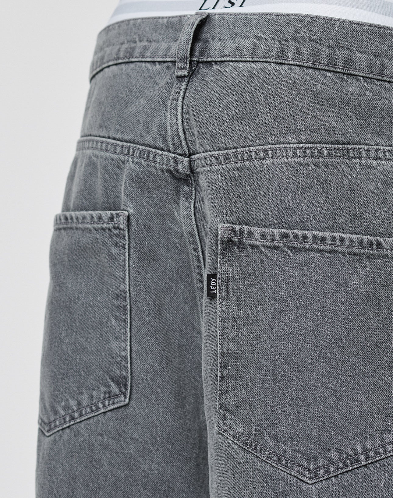 Close-up of the LFDY Baggy Denim by LIVE FAST DIE YOUNG, featuring two large back pockets, a visible waistband with a white label, and a small black tag. Made from 100% Baumwolle for comfort and style.