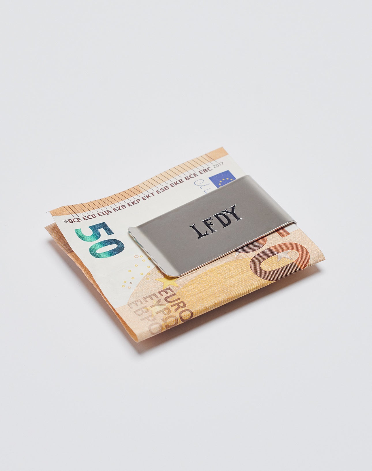 A Basic Money Clip aus Edelstahl von LIVE FAST DIE YOUNG hält gefaltete 50- und 20-Euro-Scheine auf weißem Hintergrund. Modell: LF2305-13597.