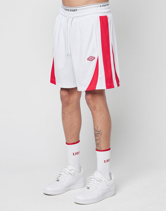 A person wears LIVE FAST DIE YOUNG Striped Mesh Shorts with a white waistband, red accents, a logo patch, white crew socks featuring red LEDI text, and white sneakers, standing against a plain white background. | model