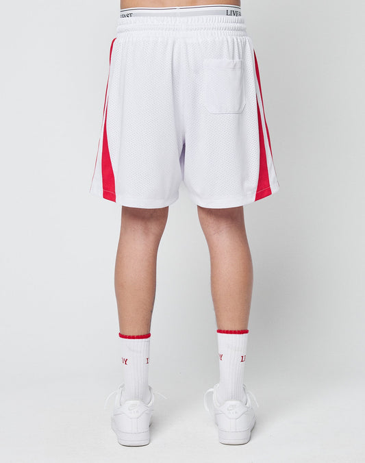 A person faces away, wearing LIVE FAST DIE YOUNG Striped Mesh Shorts—white polyester with red side stripes, a logo patch, and a single right back pocket—paired with white socks featuring red accents and white sneakers.