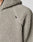 Close-up of a light gray, textured sherpa fleece Live Fast Teddy Jacket by LIVE FAST DIE YOUNG. Features a black shoulder tag, partially visible zipper, hood, and stylish nylon accents.
