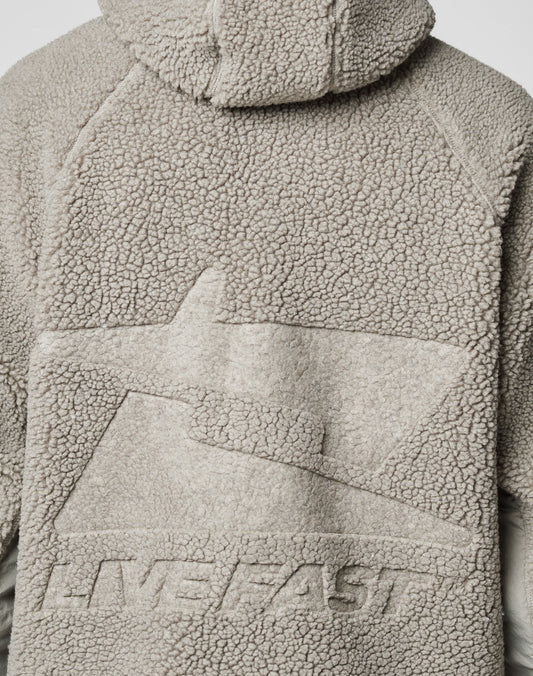Close-up of the back of the light gray Live Fast Teddy Jacket by LIVE FAST DIE YOUNG, featuring embossed abstract branding and raised “LIVE FAST” text on textured fleece fabric.