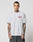 A tattooed man wears the LIVE FAST DIE YOUNG Live Fast 2013 Tee, a regular fit light gray T-shirt made from 100% Baumwolle, featuring a small red and white LIVES FAST DIE YOUNG graphic on the chest, against a plain background.