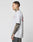 A tattooed man stands in profile wearing the LIVE FAST DIE YOUNG Live Fast 2013 Tee, a Regular Fit light gray 100% Baumwolle T-shirt, and dark jeans against a plain white background.