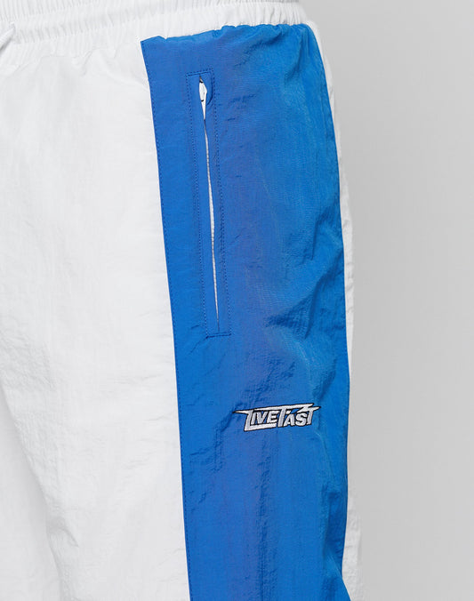 Close-up of LFDY Trackpants 3000 by LIVE FAST DIE YOUNG featuring white and blue color blocking, a vertical zippered pocket, INFAST logo on blue fabric, comfortable elastikbund, wide fit for a relaxed look, and wrinkled texture.