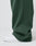 Close-up of a person wearing the LIVE FAST DIE YOUNG Basic Wide Jogger in dark green with a wide fit and elastic waistband, paired with white sneakers. The background is plain and light-colored.