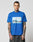 A tattooed man wears the LIVE FAST DIE YOUNG LFDY Crash Kid Tee, a blue regular fit T-shirt with a car graphic and text, standing facing forward against a plain light background.