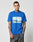 A tattooed man stands against a plain white background, wearing the LIVE FAST DIE YOUNG LFDY Crash Kid Tee— a regular fit, blue T-shirt with sports car graphics and topstitching—looking at the camera with a neutral expression.