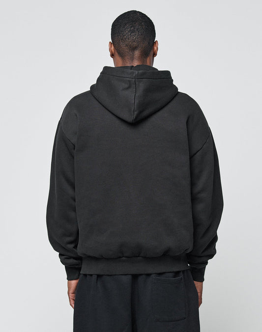 A person, back to camera, wears the LIVE FAST DIE YOUNG Basic Blank Hooded in an Oversize Fit with matching black pants made from a soft Baumwolle-Polyester blend, standing against a plain light gray background.