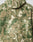 Close-up of the back of the Live Fast Teddy Jacket by LIVE FAST DIE YOUNG, showcasing textured, fleece-like fabric in green and beige camouflage with a hood featuring a visor opening.