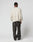 A person faces away in a cream LFDY Praying Fuzzy Sweater by LIVE FAST DIE YOUNG, featuring an oversize fit and intarsia logo on the back, rundhals neckline, and paired with loose dark leather pants against a plain white background.