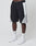 A person in black, gray, and white LIVE FAST DIE YOUNG Basic Nylon Trackshorts with elastic waistband and logo embroidery, white LFDY socks, and white sneakers stands against a plain white background.