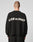 A person with short hair is seen from behind wearing the LIVE FAST DIE YOUNG Live Fast Boucle Sweater in black, featuring a white LIVE FAST slogan on the back, an oversize fit, and set against a plain light background.