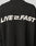 The LIVE FAST DIE YOUNG Live Fast Boucle Sweater is a black oversized polyester sweater with bold white LIVE FAST text—lightning bolt as the I—on the back, designed for all-day comfort.