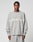 A person wears the LIVE FAST DIE YOUNG Live Fast Boucle Sweater in an oversized light gray fit with matching pants. The 100% polyester sweater displays blurred white LIVE FAST text across the chest. The background is plain and light-colored.
