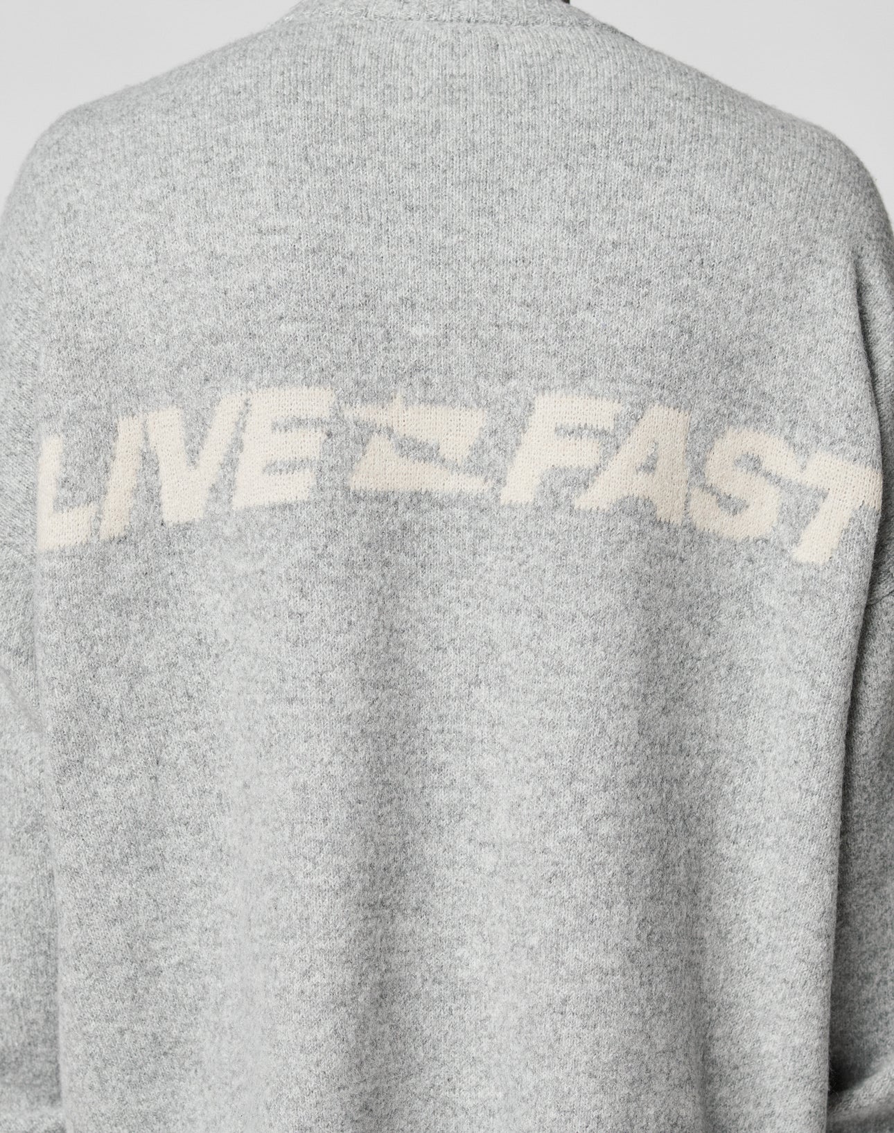 The Live Fast Boucle Sweater by LIVE FAST DIE YOUNG is a gray, 100% polyester piece with an oversize fit and bold white LIVE FAST lettering across the upper back.