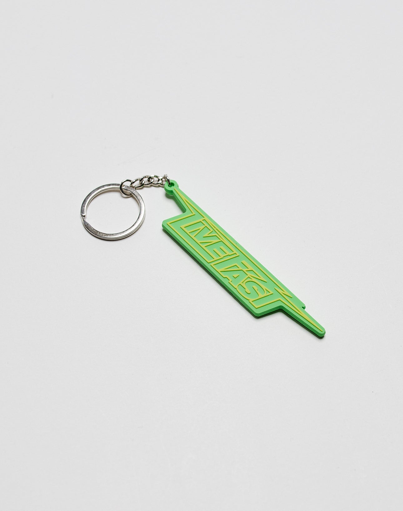 A green Live Fast Keychain by LIVE FAST DIE YOUNG, featuring INSTANT in yellow on silicone and attached to a metal ring, rests on a plain white surface.