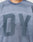 Close-up of a person wearing the LIVE FAST DIE YOUNG Faded Waffle Jersey, an oversized, textured blue shirt made from 100% Baumwolle with large blurred DY letters on the faded front; only neck and upper torso are shown.