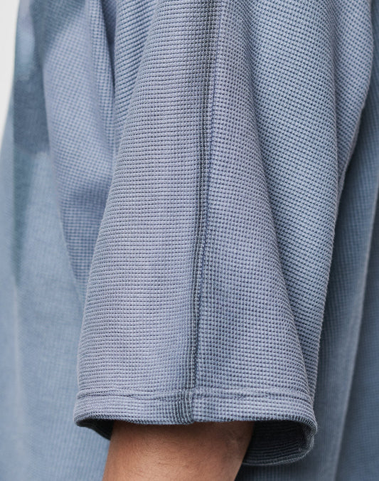 Close-up of a person’s arm in the LIVE FAST DIE YOUNG Faded Waffle Jersey, featuring light blue textured 100% Baumwolle fabric and an Oversize Fit. Only part of the shirt and arm are visible, showcasing its modern comfort and style.
