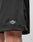 Close-up of the lower part of LIVE FAST DIE YOUNG Basic Mesh Shorts in black, featuring an elastic waistband and a white LIVE FAST logo patch on the hem, made from 100% polyester and worn by a light-skinned person.