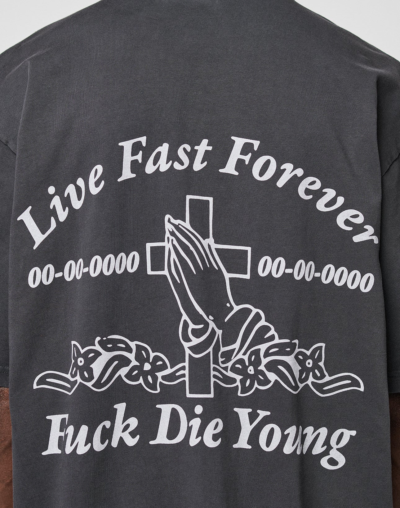 The LFDY Praying Tee by LIVE FAST DIE YOUNG is a dark, 100% cotton oversized T-shirt featuring front and back prints of praying hands before a cross with flowers and bold white Live Fast Forever Fuck Die Young text.|