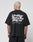 A person with short blond hair is seen from behind wearing the LIVE FAST DIE YOUNG Basic 280 Tee, an oversize black cotton T-shirt with bold white front and back prints and smaller text beneath.