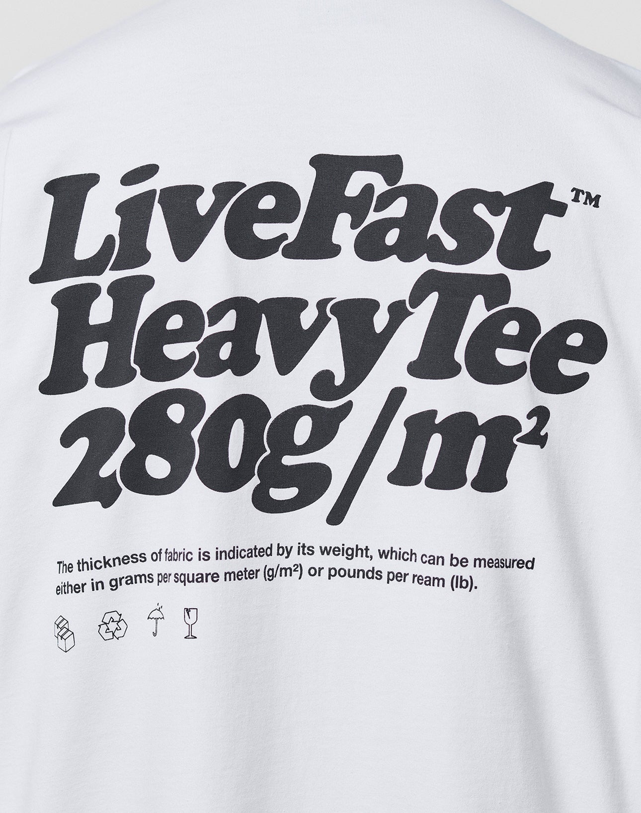 A white Oversize Fit Basic 280 Tee by LIVE FAST DIE YOUNG, with bold black text: Live Fast Heavy Tee 280g/m². Smaller text notes fabric thickness in grams/m² and lbs/ream, plus laundry icons. Made from 100% Baumwolle.