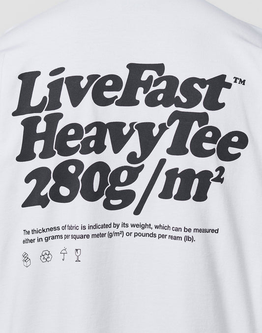 A white Oversize Fit Basic 280 Tee by LIVE FAST DIE YOUNG, with bold black text: Live Fast Heavy Tee 280g/m². Smaller text notes fabric thickness in grams/m² and lbs/ream, plus laundry icons. Made from 100% Baumwolle.