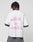 A person with short, twisted hair faces away from the camera, wearing the LFDY Against us Tee by LIVE FAST DIE YOUNG—an oversize white 100% Baumwolle t-shirt featuring a pink “WITH US OR AGAINST US” frontprint. The background is plain and light.