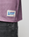 A close-up of a person wearing the LFDY Flash Jersey by LIVE FAST DIE YOUNG in oversize purple mesh, featuring a white rectangular patch labeled LFDY and OFFICIALLY LICENSED PRODUCT above black jeans with white paint splatters. Size M.